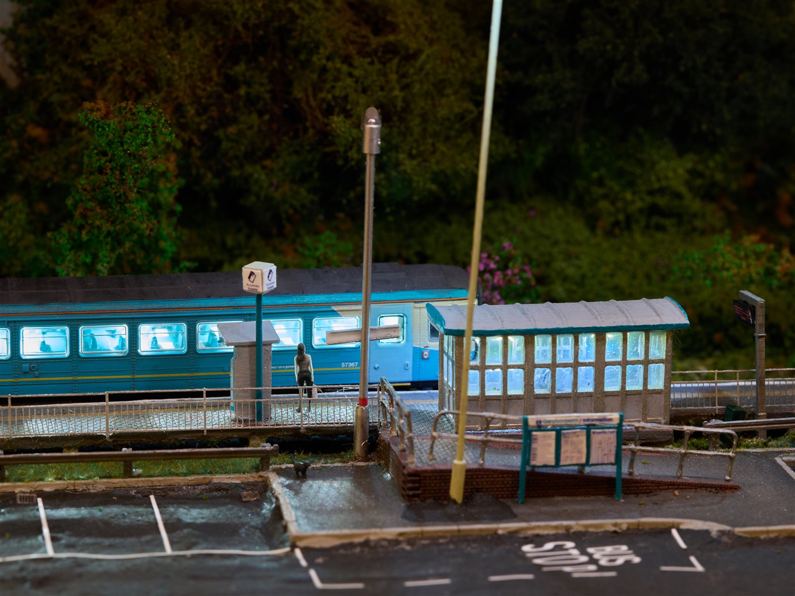Illuminated platform shelter and waiting passenger at dusk