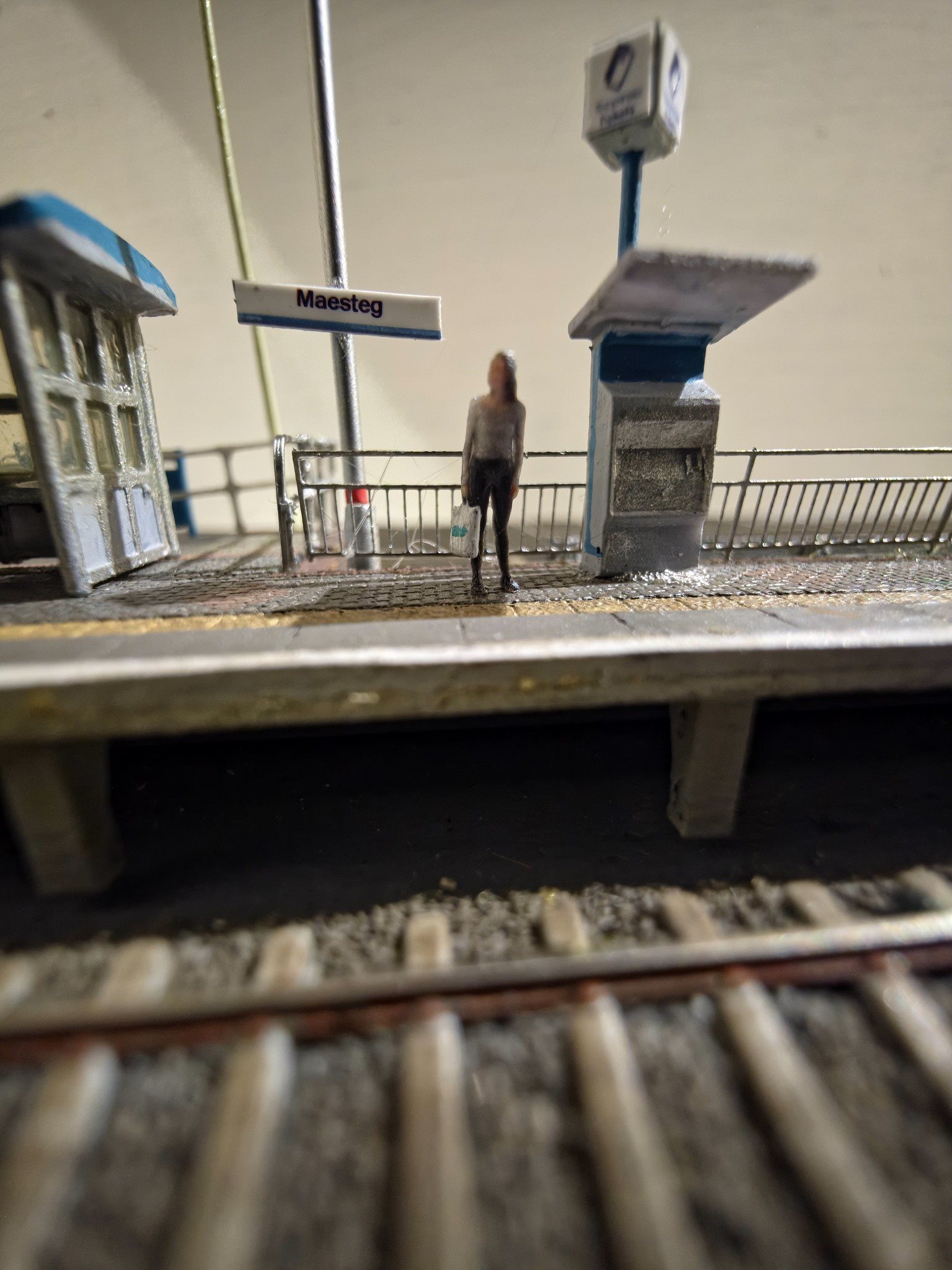 Close-up of platform Maesteg station sign, passenger, and ticket machine